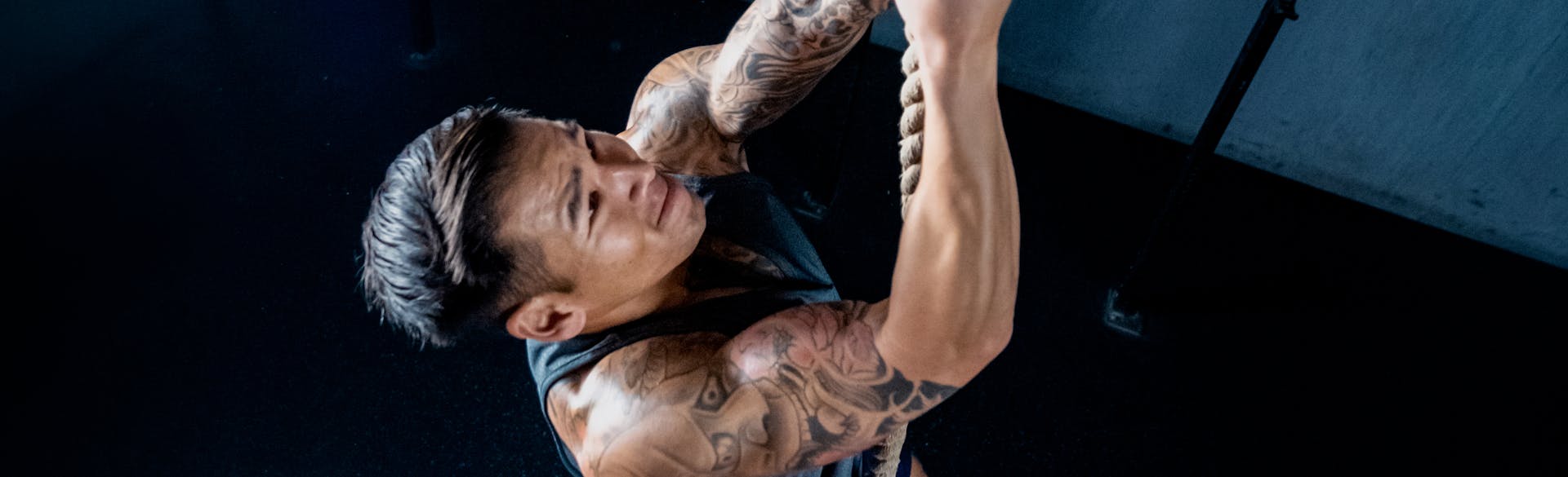 Don Tran climbing a rope in a gym.